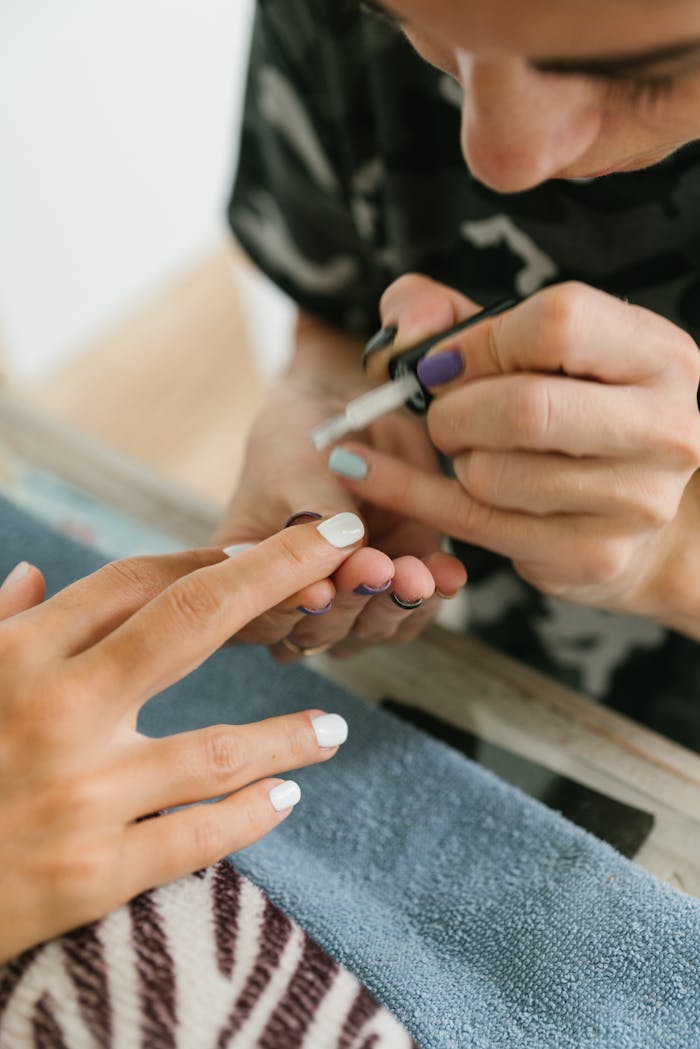 Detailed view of a manicurist painting nails indoors, showcasing precision and care.